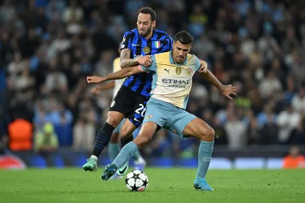 MANCHESTER, ENGLAND - SEPTEMBER 18: Rodri of Manchester City is challenged by Hakan Calhanoglu of FC Internazionale during the UEFA Champions League 2024/25 League Phase MD1 match between Manchester City and FC Internazionale Milano at City of Manchester Stadium on September 18, 2024 in Manchester, England.