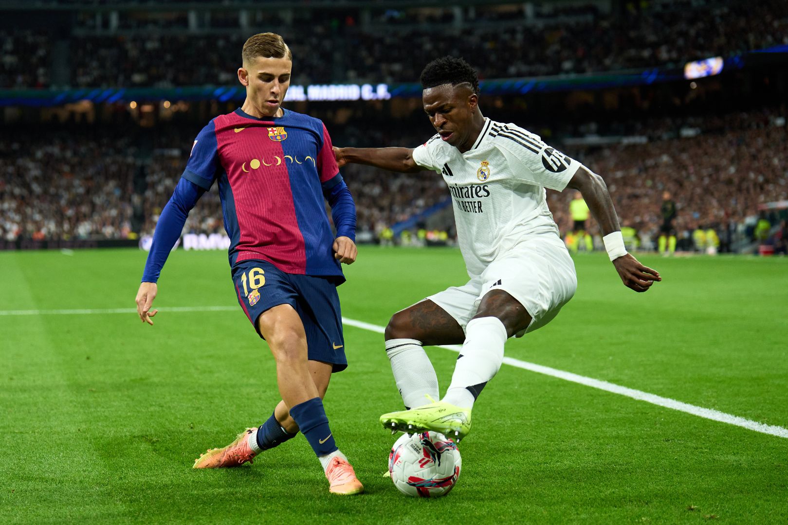 MADRID, SPAIN - OCTOBER 26: Vinicius Junior of Real Madrid is challenged by Fermin Lopez of FC Barcelona during the LaLiga match between Real Madrid CF and FC Barcelona at Estadio Santiago Bernabeu on October 26, 2024 in Madrid, Spain. 