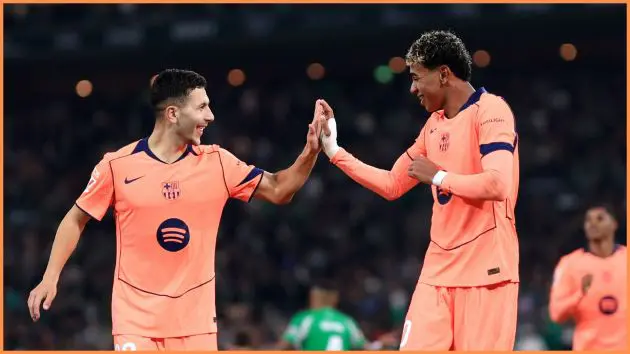 SEVILLE, SPAIN - DECEMBER 06: Lamine Yamal of FC Barcelona celebrates scoring his team's fifth goal from the penalty spot with teammate Roony Bardghji during the LaLiga EA Sports match between Real Betis Balompie and FC Barcelona at Estadio La Cartuja on December 06, 2025 in Seville, Spain.