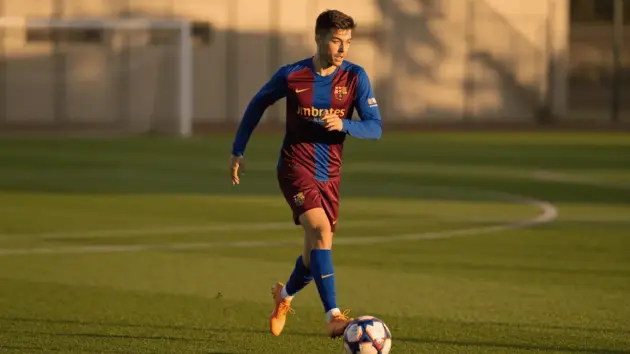Young footballer in Barca colors sprinting down left flank during training session