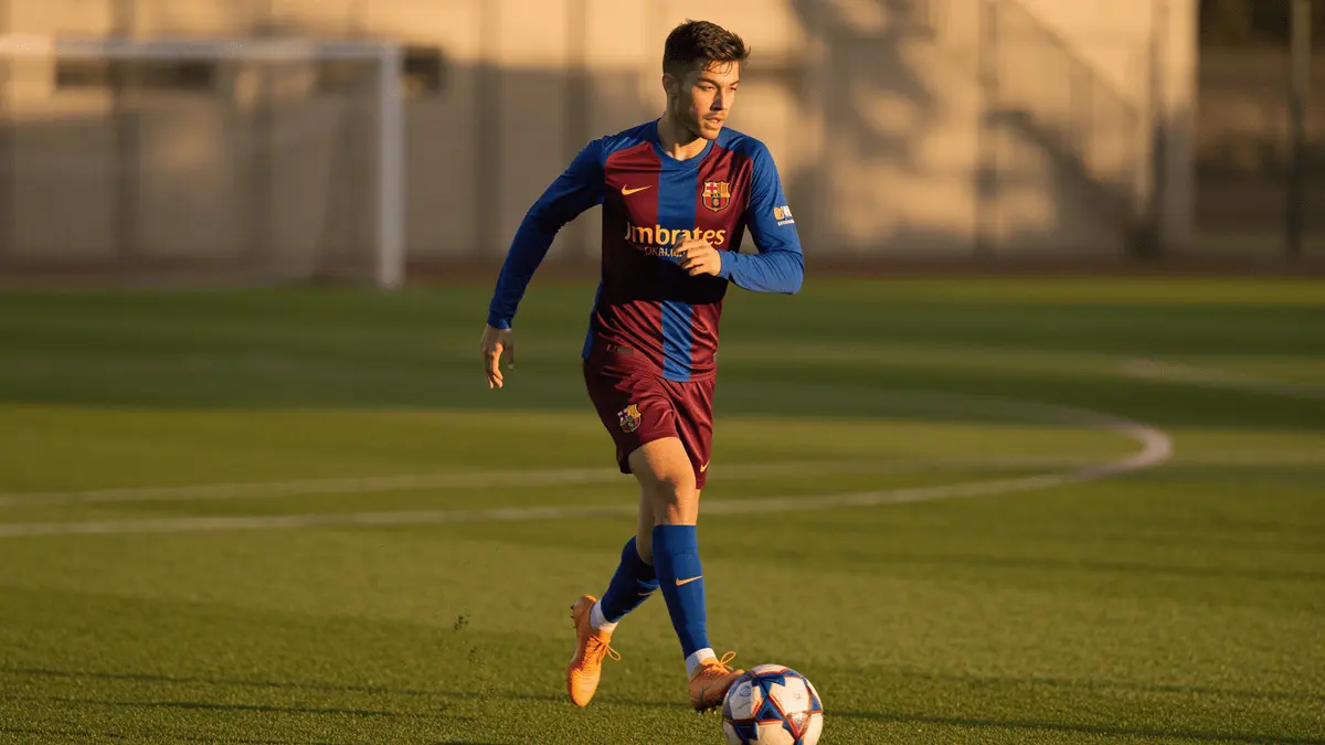 Young footballer in Barca colors sprinting down left flank during training session