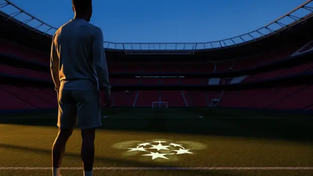 Striker silhouette gazing at stadium pitch with Champions League ambition in blue and claret tones