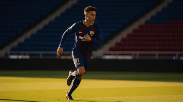 Young Barcelona footballer moving from wing to central position on Camp Nou pitch at golden hour