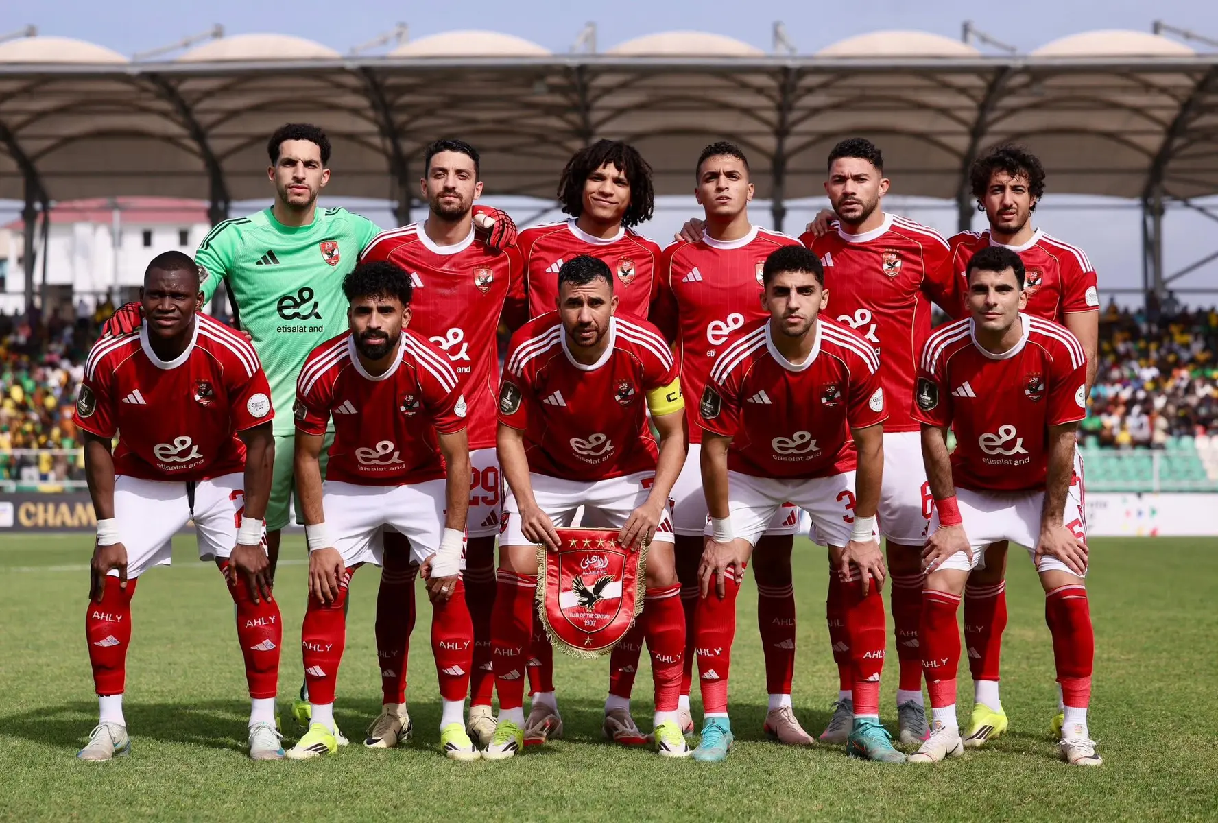 Al Ahly SC football team posing for a group photo on the pitch in their red home kits.