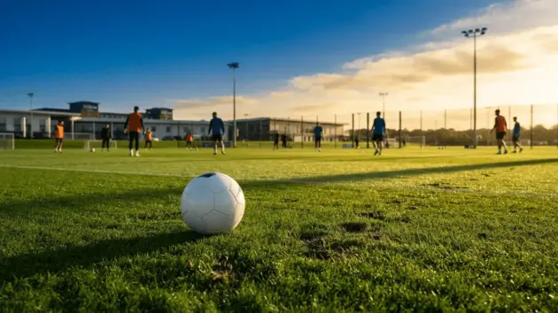 St George's Park training facility at golden hour with football on pristine grass pitch