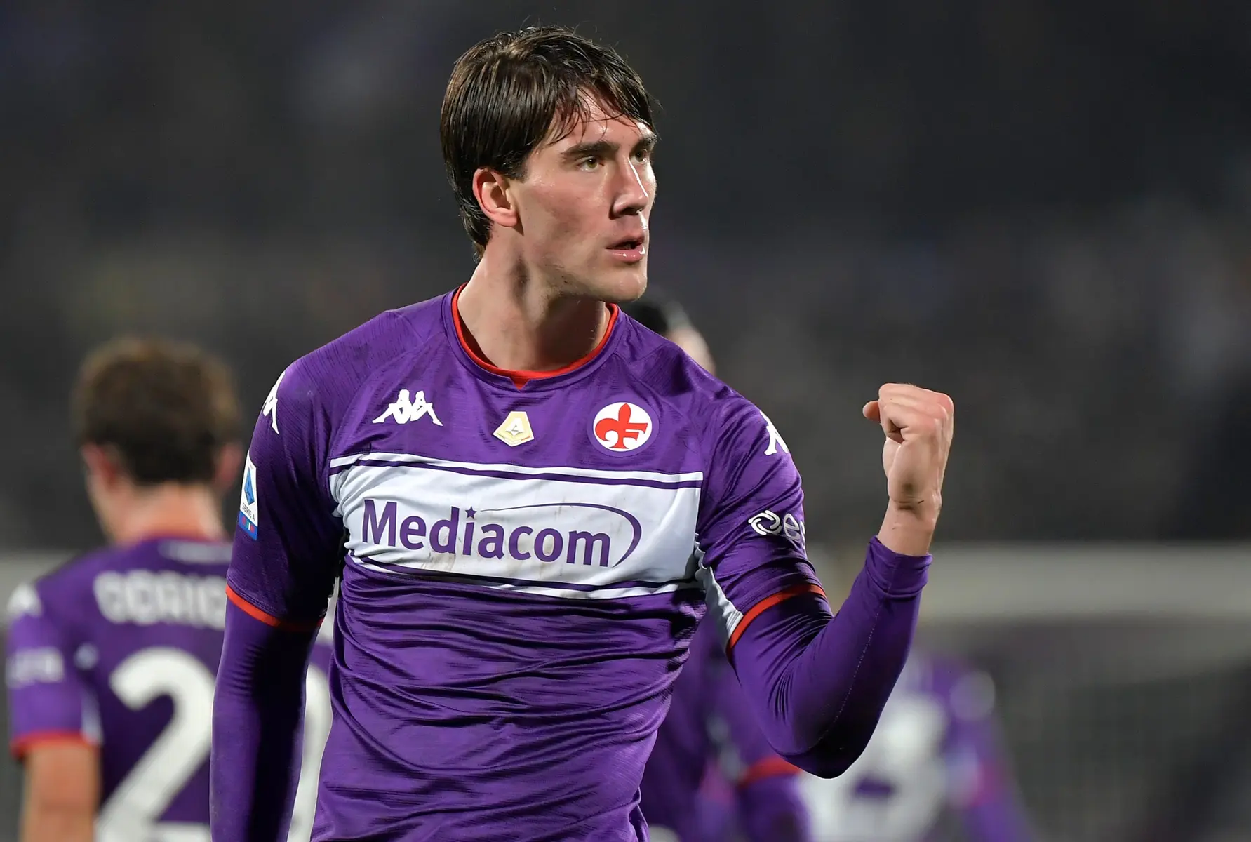 Dusan Vlahovic celebrating a goal in a purple Fiorentina jersey.