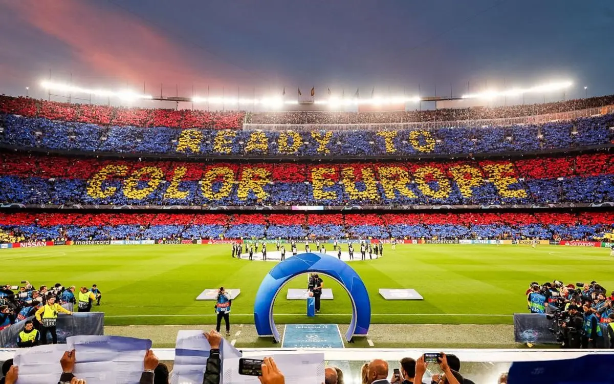Wide view of Camp Nou stadium with fans holding colored cards to form a mosaic saying READY TO COLOR EUROPE