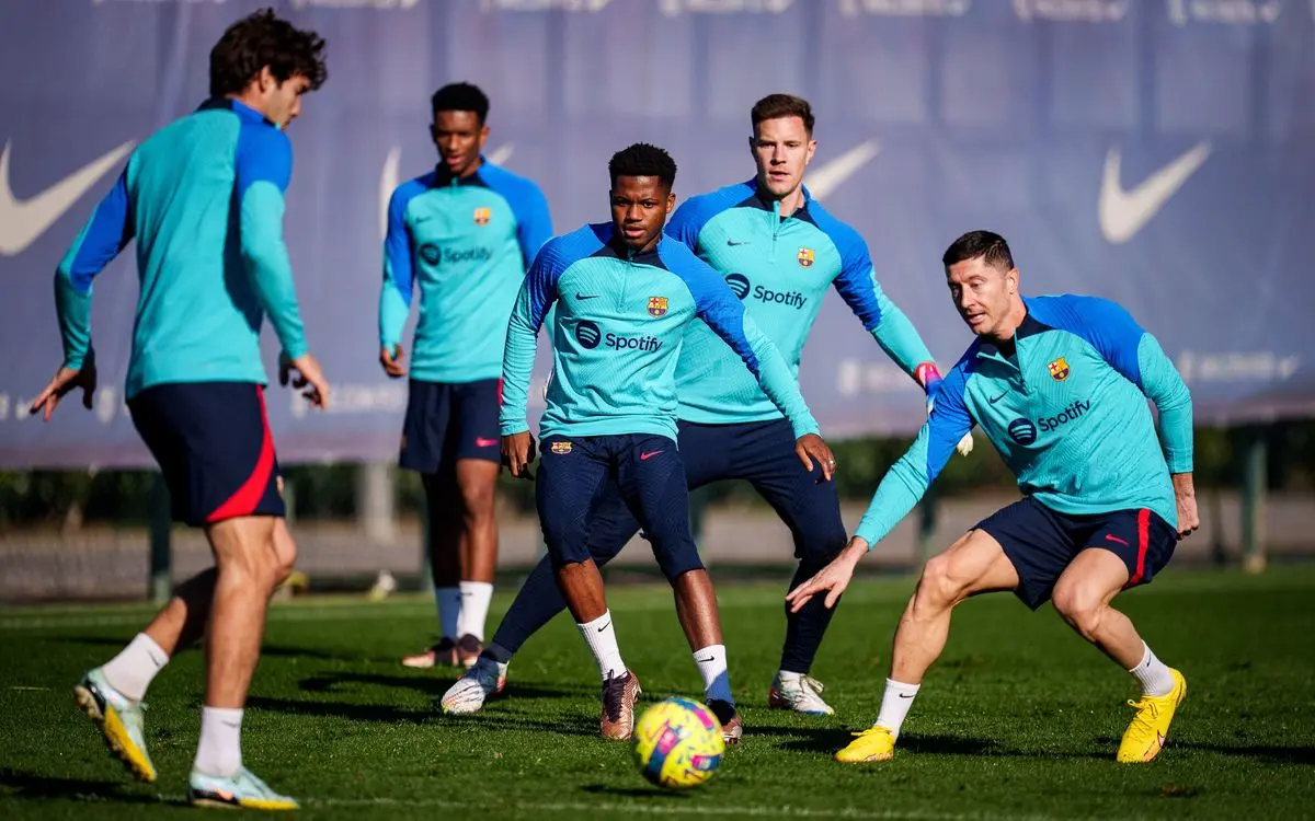 FC Barcelona players in blue training gear practicing with a soccer ball on a grass field