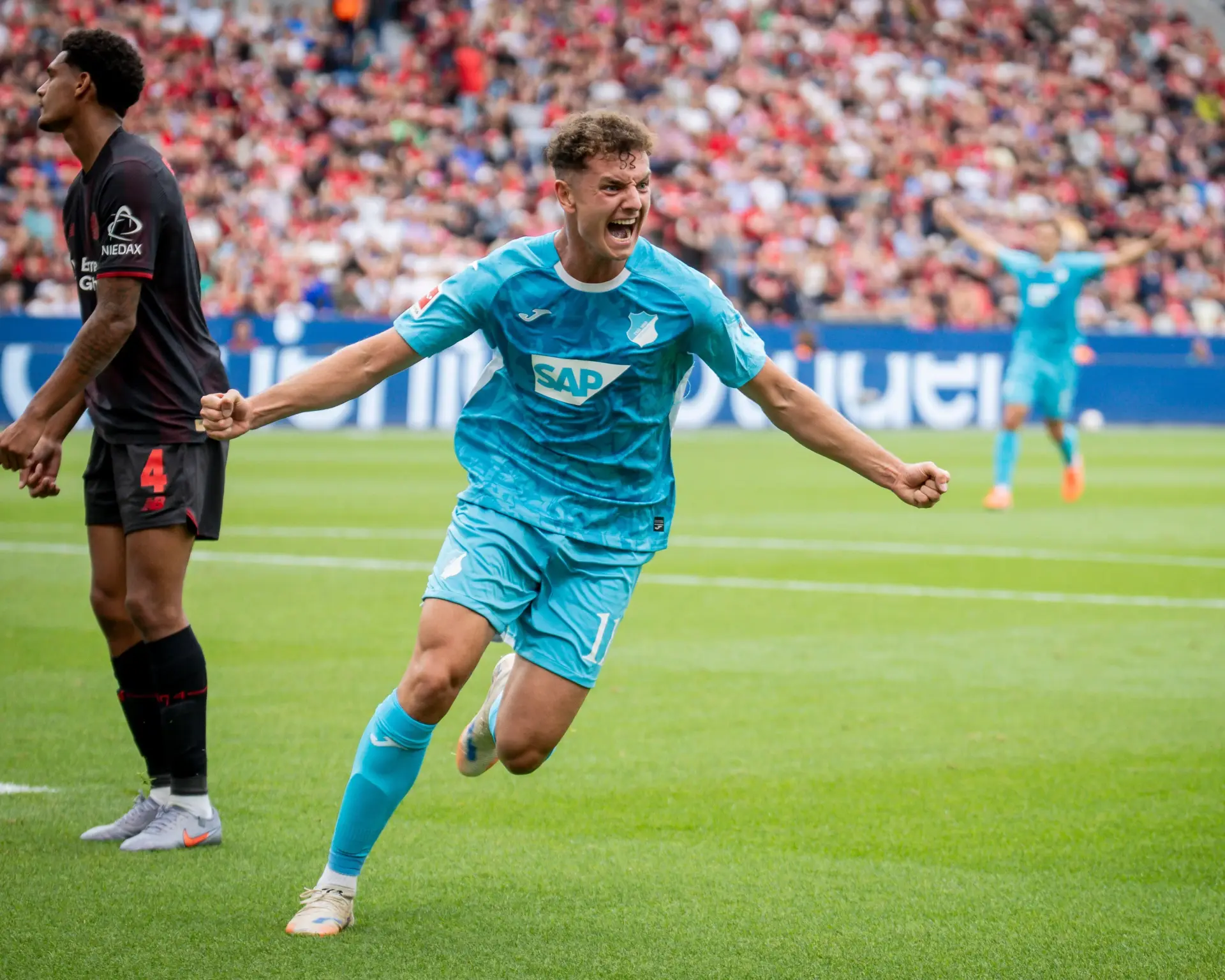 A football player celebrating in blue kit during a match.