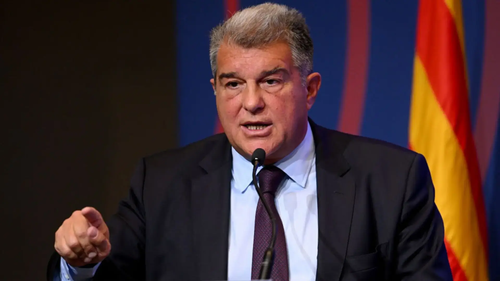 Joan Laporta speaking at a press conference with a microphone.