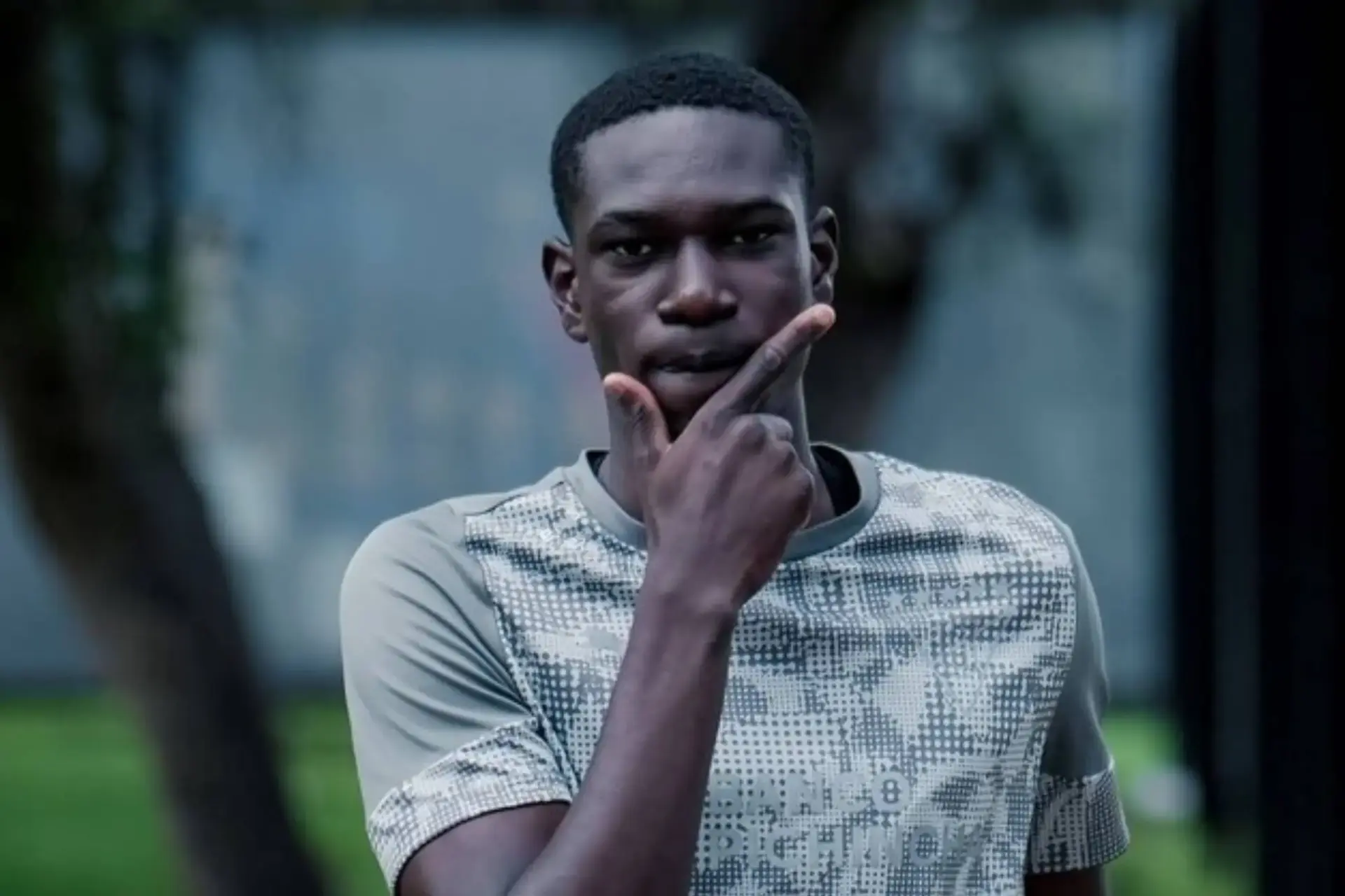 Josue Caicedo wearing a patterned sports shirt, posing thoughtfully outdoors.