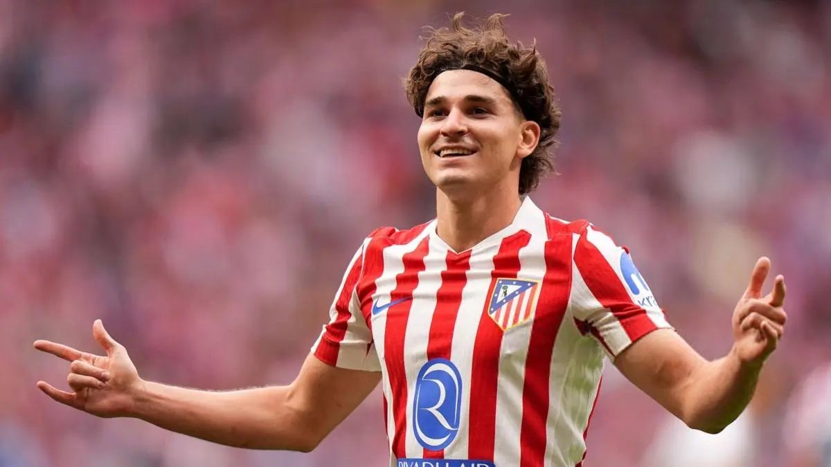 Julian Alvarez celebrating in Atletico Madrid's red and white striped jersey.