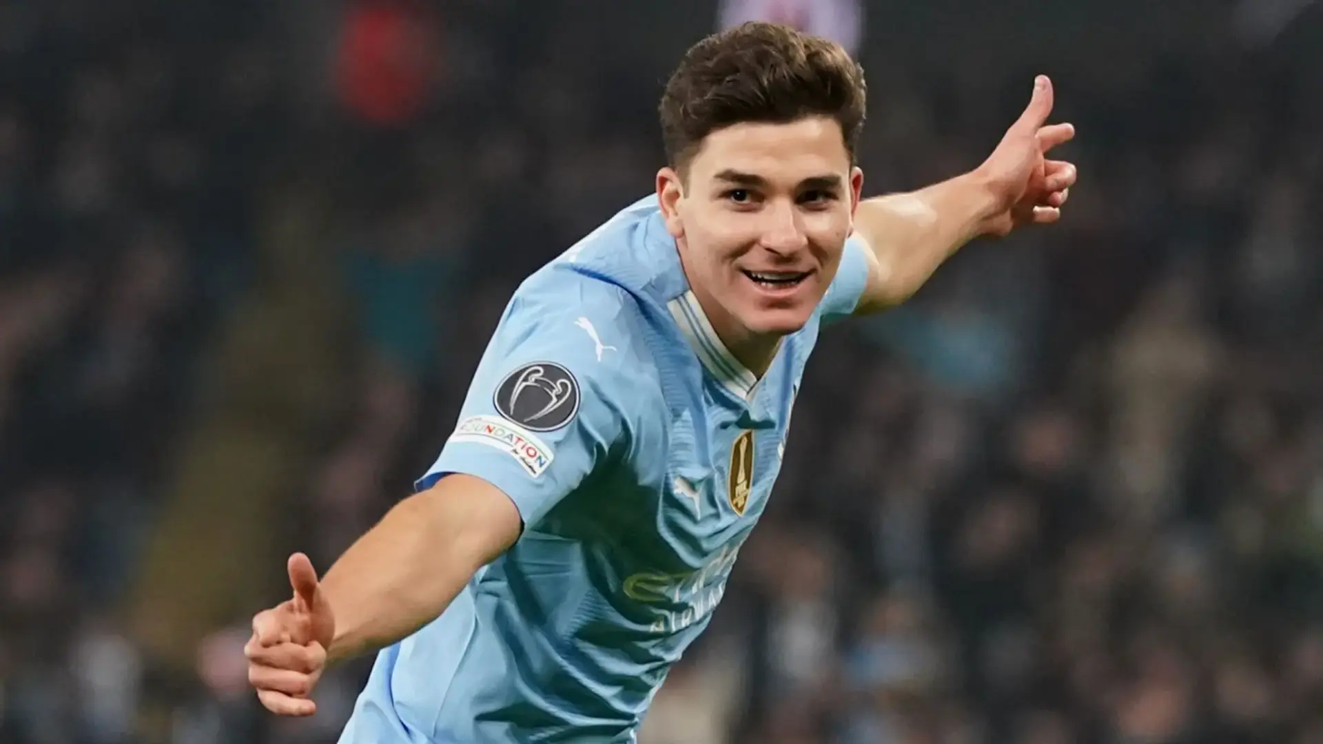 Julian Alvarez celebrating a goal wearing a light blue Manchester City jersey.