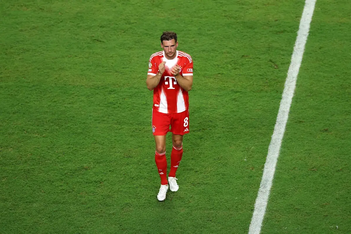 Leon Goretzka in a red Bayern Munich kit clapping on a green football pitch
