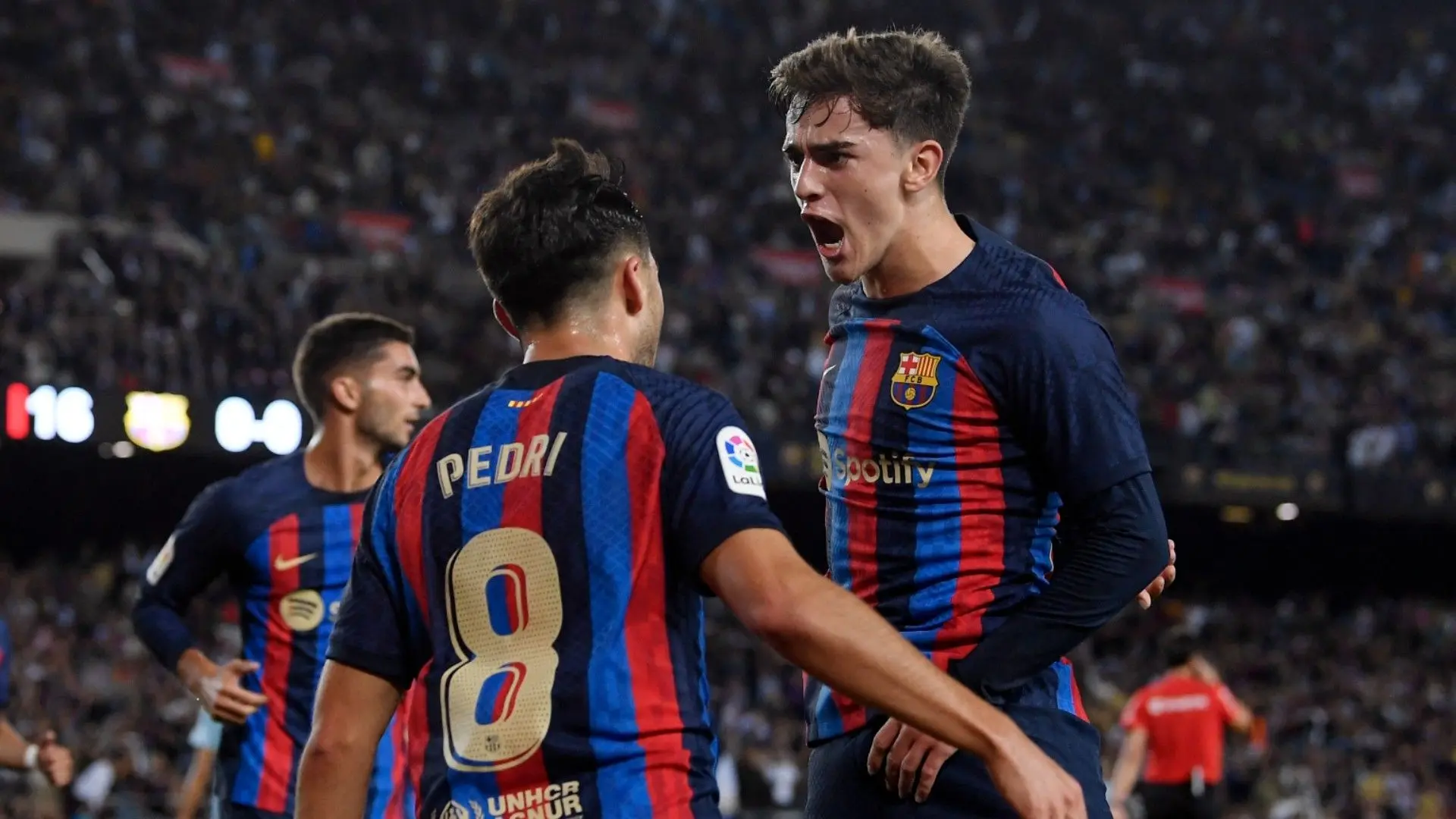 Pedri and Gavi celebrating a goal in FC Barcelona home jerseys during a match.