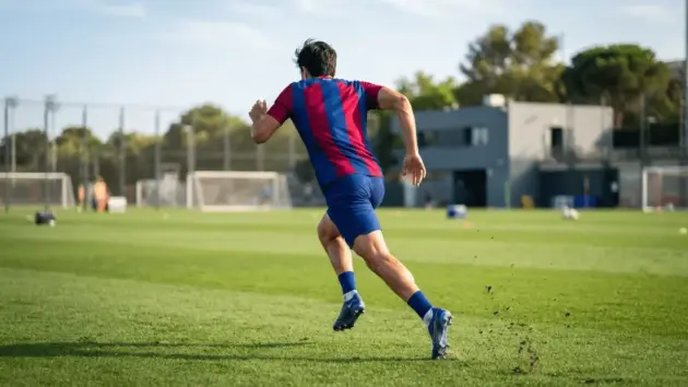 Raphinha in FC Barcelona jersey sprinting on training pitch during pre-season preparation