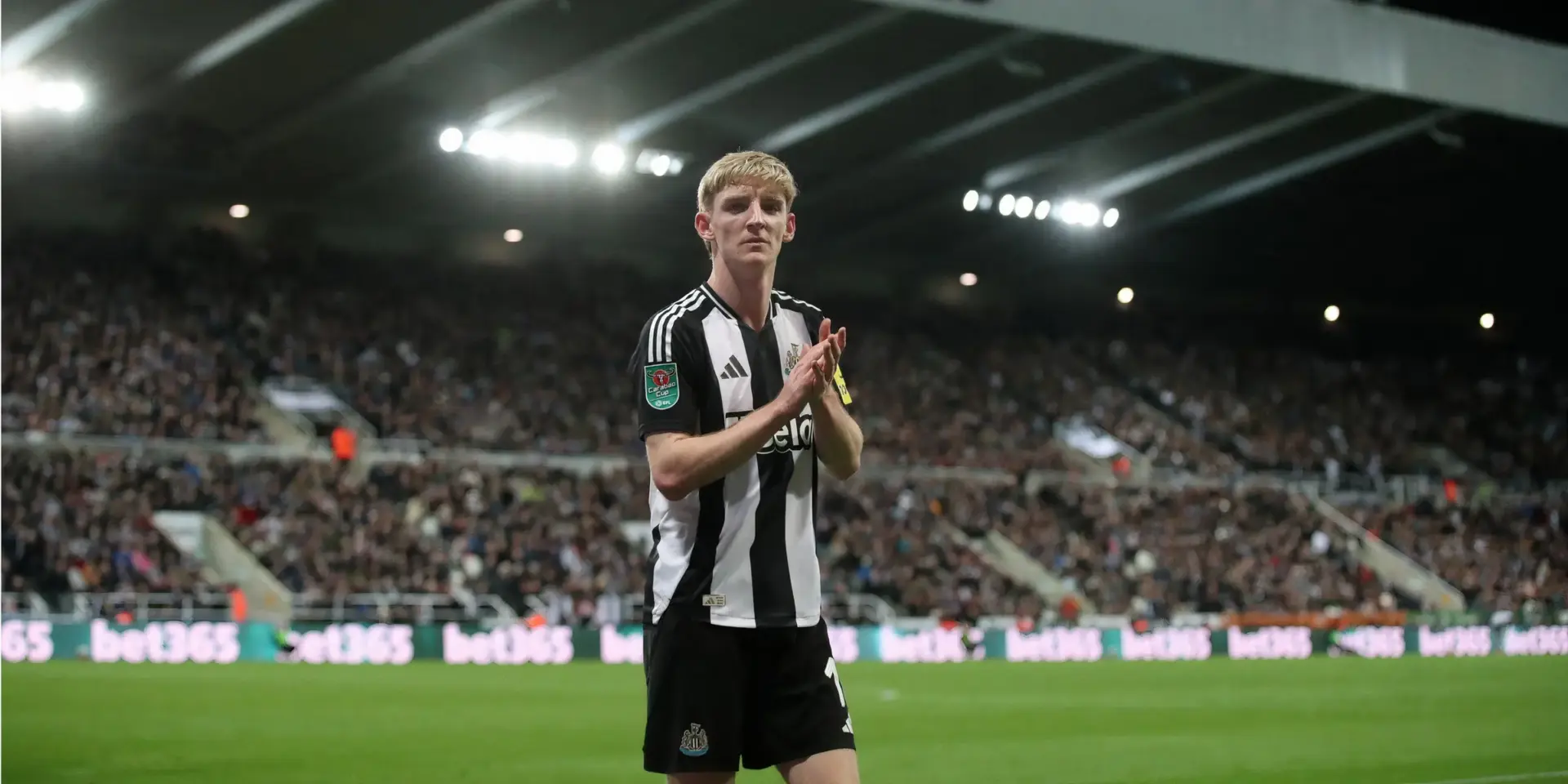 Anthony Gordon in a Newcastle United black and white striped kit clapping during a match.