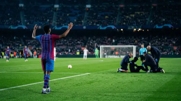Barcelona player celebrates a 5-0 win as a distant teammate receives attention during a tense La Liga match