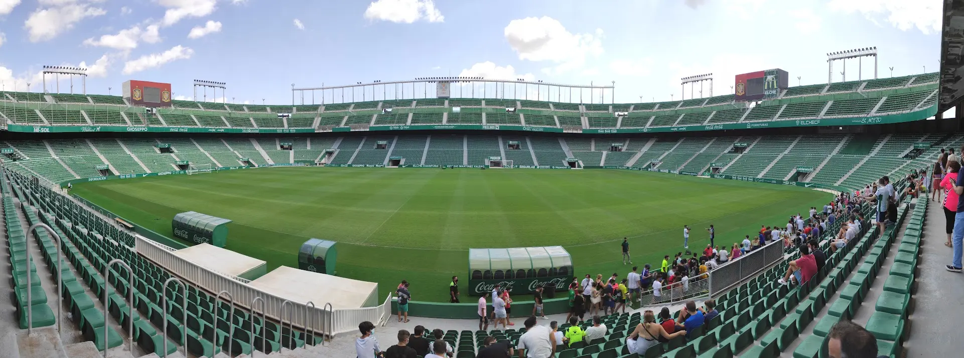Panoramic wide shot of the Estadio Manuel Martínez Valero in Elche with green seats and a lush grass pitch.