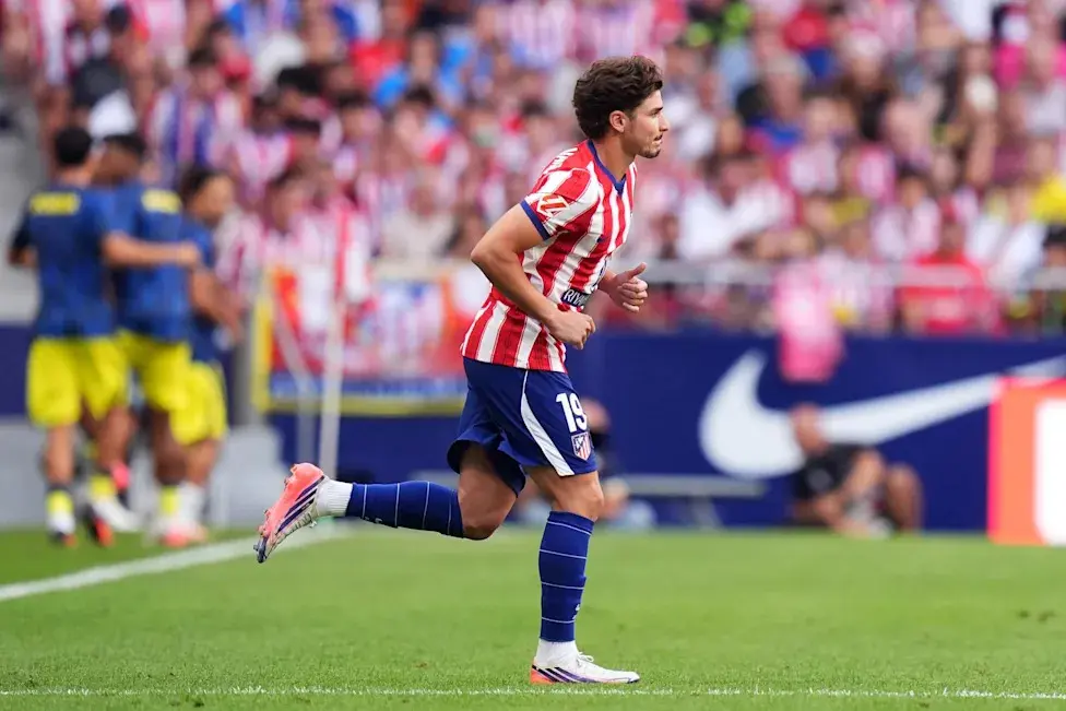 Julian Alvarez running on the pitch wearing the Atletico Madrid red and white striped home kit