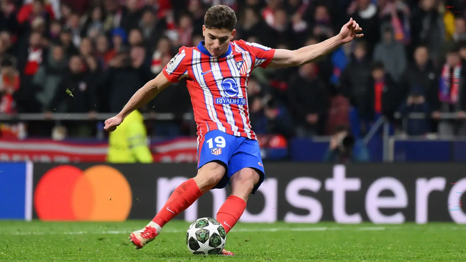 Julian Alvarez in Atletico Madrid kit kicking a soccer ball during a match