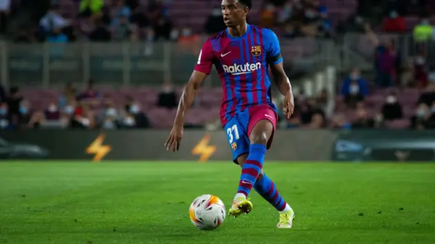 Alejandro Balde in a Barcelona kit dribbling a football during a match.