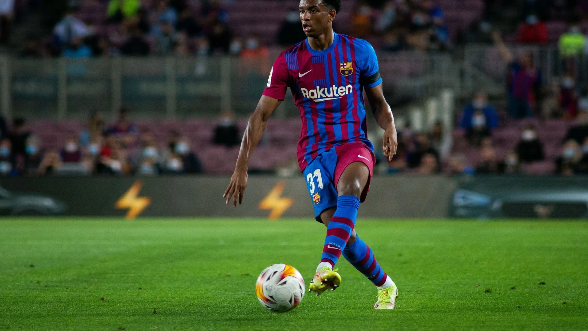 Alejandro Balde in a Barcelona kit dribbling a football during a match.
