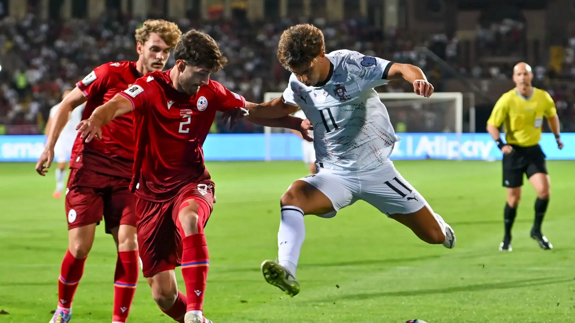João Félix in a white Portugal national team kit competing for the ball against a player in a red kit.
