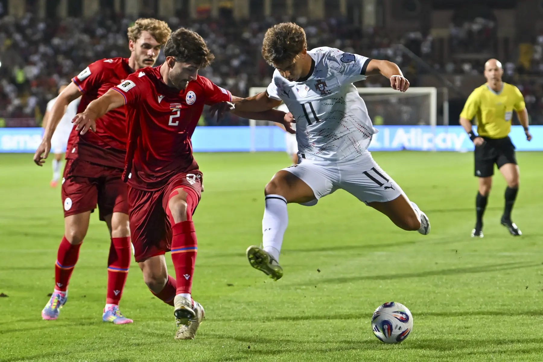 João Félix in a white Portugal national team kit competing for the ball against a player in a red kit.