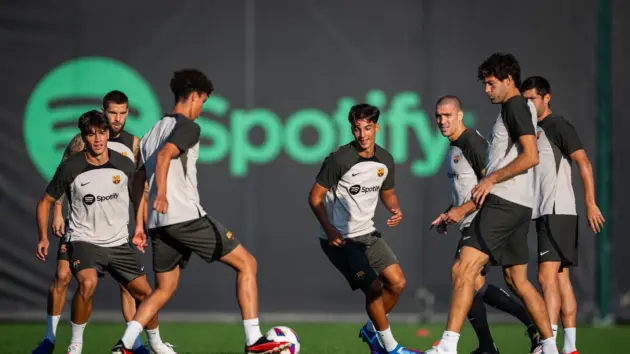 FC Barcelona players in training gear during a session on a grass pitch.