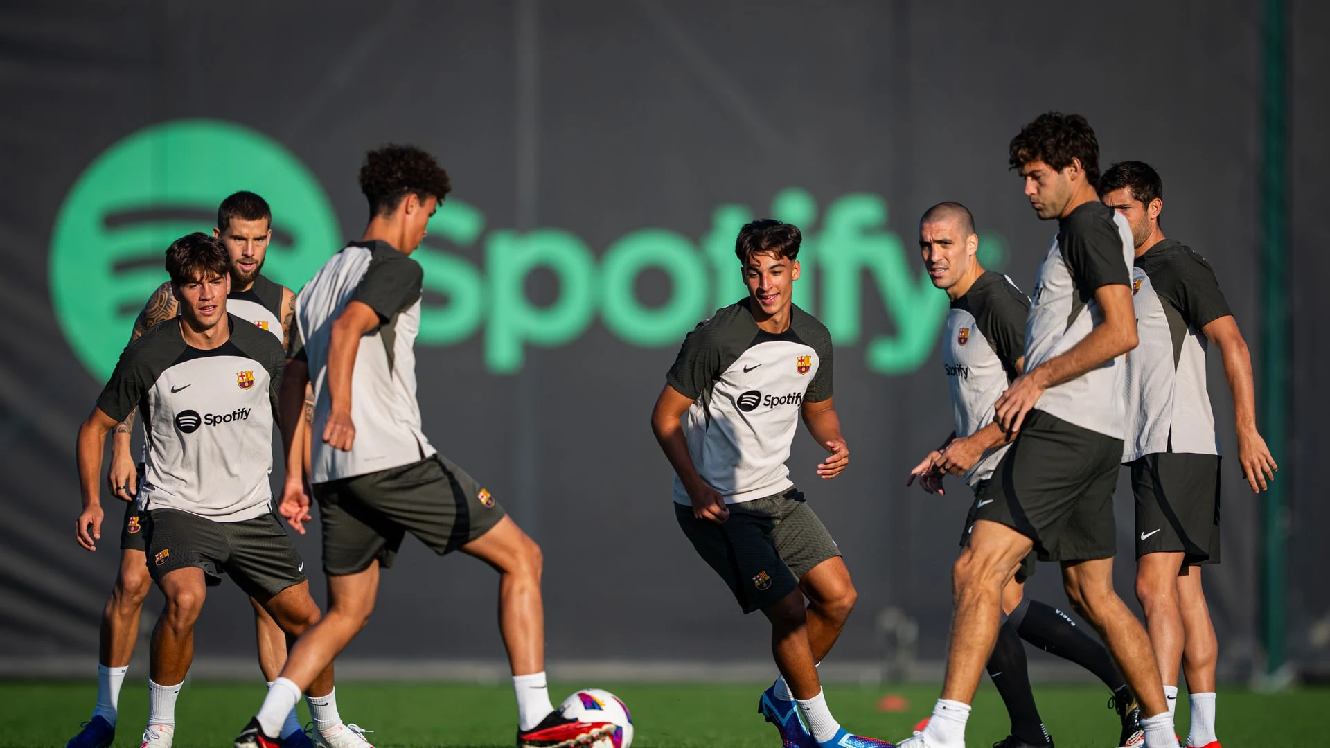 FC Barcelona players in training gear during a session on a grass pitch.