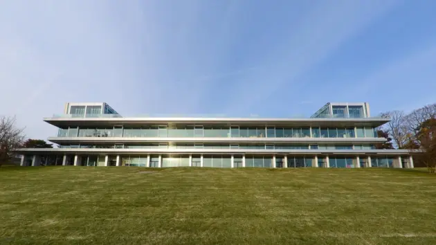 The modern exterior of the UEFA Campus building situated on a green lawn under a clear blue sky.